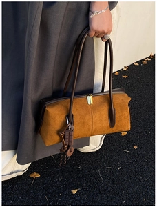Détail du sac Boston en daim marron avec poignées en cuir et breloque chocolat