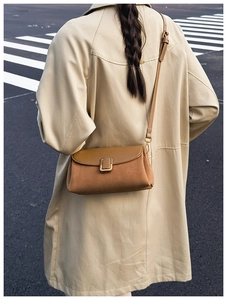 Brown vintage suede crossbody bag styled with a beige trench coat for a chic autumn look