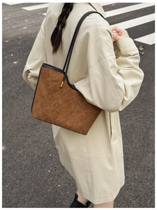 Close-up of brown quilted shoulder bag with suede texture and gold hardware on a model
