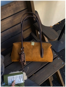 Détail d'un sac Boston en daim marron avec fermetures dorées et pendentif en chocolat