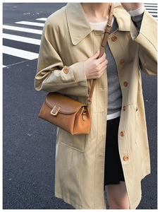 Chic brown leather crossbody bag styled with beige trench coat for a city commute look