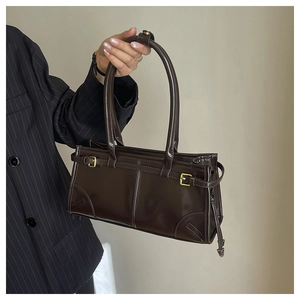 Detail of a dark brown vintage faux leather shoulder bag with gold buckle decoration