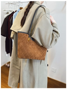 Brown suede tote bag with diamond quilting and slender straps shown on shoulder