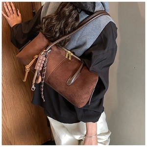 Détail d'un sac à bandoulière en daim marron avec pendentif chocolat et décor de corde tressée