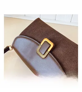 Detail view of coffee leather handbag featuring matte suede trim and a gold buckle