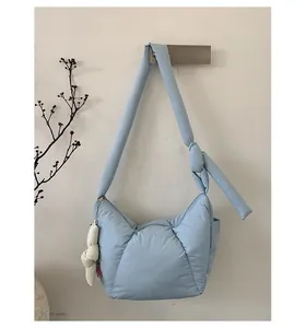 Close-up of light blue padded nylon dumpling bag with knot handle and fashion charm