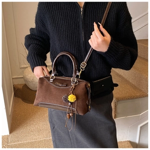 Brown suede crossbody bag shown on a model featuring a cute plush pompom bag charm