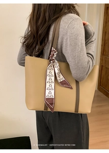 Detail of khaki tote bag with dark brown leather straps and patterned silk scarf accent