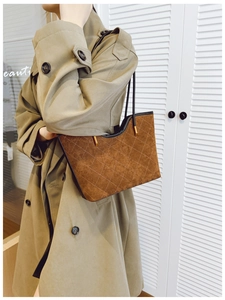 Close-up of brown quilted suede handbag with U-shaped design and black handles