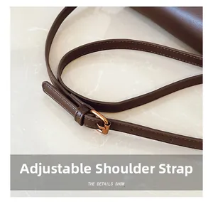 Detailed macro view of adjustable brown leather shoulder strap with gold metal buckle