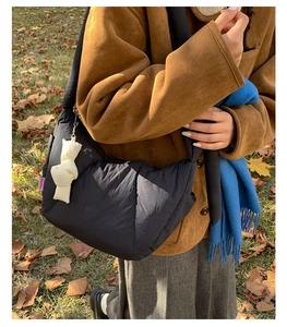 Outdoor shot of a black quilted dumpling bag with a white knot charm and purple label