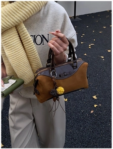 Detail of vintage Boston handbag with leather texture and pom-pom charm on autumn background