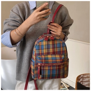 Dettaglio dello zaino in tweed a quadri colorati con spallacci rossi e multitasche