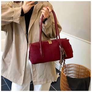 Détail du sac Boston en daim bordeaux avec de longues anses et un pompon vintage