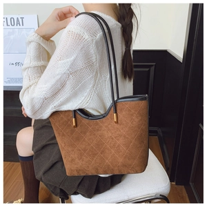 Detail of brown quilted suede tote bag with black straps and elegant gold hardware