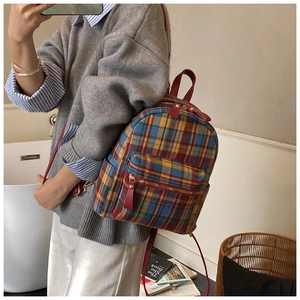 Dettaglio dello zaino in lana a quadri colorati con cinturini in pelle rossa e doppia zip