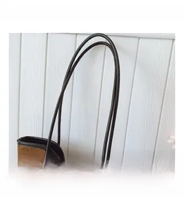 Detail of dark brown quilted tote bag with matte finish and elegant golden metal hardware