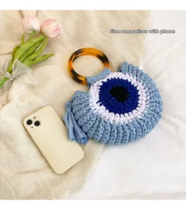 Comparaison de taille d'un sac Evil Eye au crochet avec un smartphone en gros plan