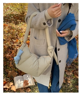 Quilted puffer bag in cream beige shown on shoulder in an autumn park setting
