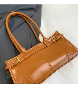 Detailed view of brown faux leather underarm bag with gold buckles and fine stitching