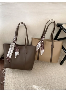 Detail of minimalist leather tote bags with printed silk scarves on a cozy carpet