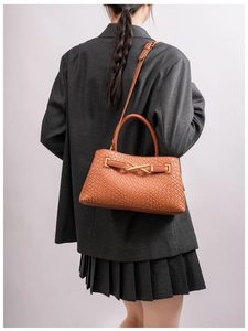 Rear view of model wearing brown woven leather handbag with elegant gold X hardware detail