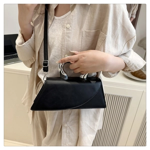 Detail of a black crossbody bag with a unique silver liquid metal handle and leather strap