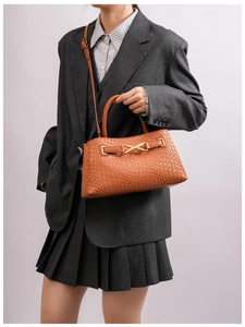 Detail of brown woven leather handbag with gold X-shaped hardware and shoulder strap