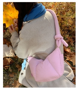 Detail of pink puffy crossbody bag with padded knot strap and fashion woven label