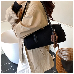 Détail du sac Boston noir avec breloque chocolat et gland sur un manteau kaki