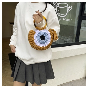Détail du sac cabas au crochet avec motif œil, anses ambre et pompons marrons