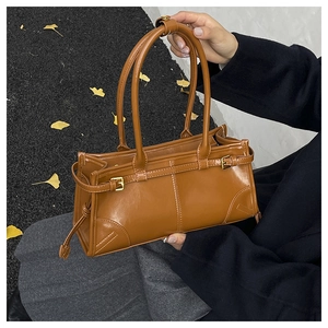 Brown vintage leather underarm bag with long straps and gold buckle detail on street
