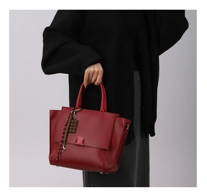 Detail van rode tas van generfd leer met chocoladehanger en gevlochten sleutelhanger decor