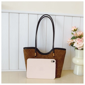 Detail of a brown quilted suede tote bag with a tablet showing size perspective