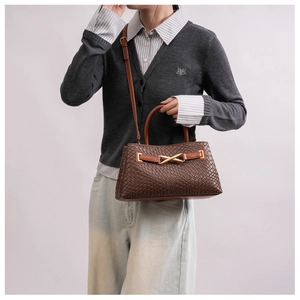 Close-up of dark brown woven texture handbag with golden X-shaped metal buckle