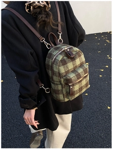 Close-up of green and brown plaid plush mini backpack with vintage leather straps