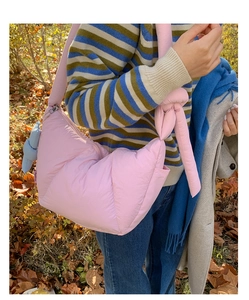 Detailed view of pink quilted puffer bag featuring a large decorative knot and plush charm