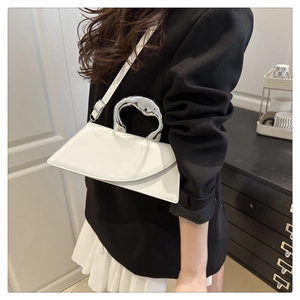 Modern white geometric handbag with silver metallic handle shown on model in stylish suit