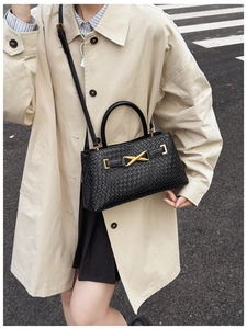 Detailed view of black woven texture leather bag with elegant gold metal buckle on street