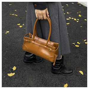 Close-up of vintage brown leather handbag with metallic buckle details and slim handles