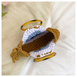 Détail du sac cabas tricoté bicolore avec anses en résine et pompon décoratif