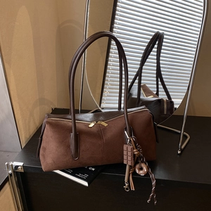 Détail du sac Boston vintage marron avec texture daim, zips dorés et pendentifs