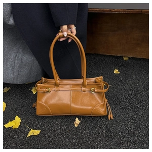 Close-up of caramel leather shoulder bag with vintage buckles and fringe details