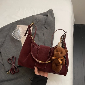 Burgundy half-moon shoulder bag with metal arch detail and cute bear charm accessory