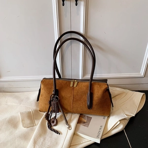 Détail d'un sac Boston en daim marron avec double fermeture éclair et pendentifs