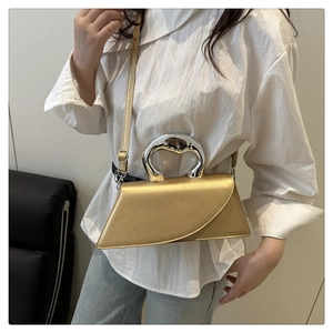 Chic gold crossbody bag with unique metal handle shown styled with a modern casual outfit