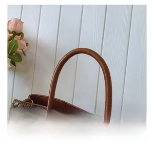 Detail of woven brown leather texture and smooth cylindrical handle with gold buckle