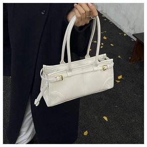 Close-up of white leather underarm bag with gold buckles held over a black coat