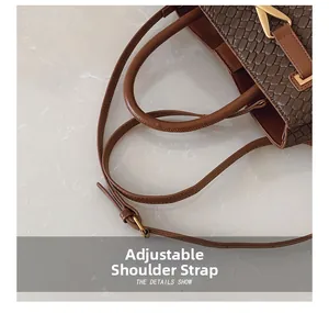 Detail of adjustable leather strap and gold metal hardware on brown woven handbag