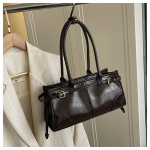 Close-up of dark brown glossy leather shoulder bag with gold buckles and chic vintage style